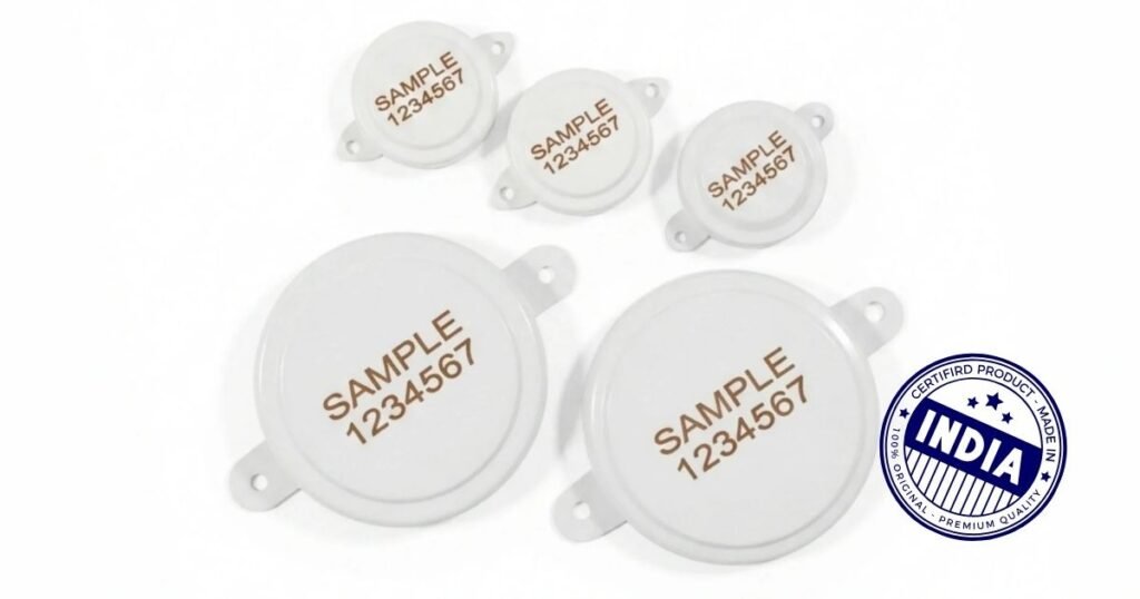 White circular sample labels with brown text reading 'SAMPLE 1234567' scattered on a white background, with an India certification stamp in the corner.