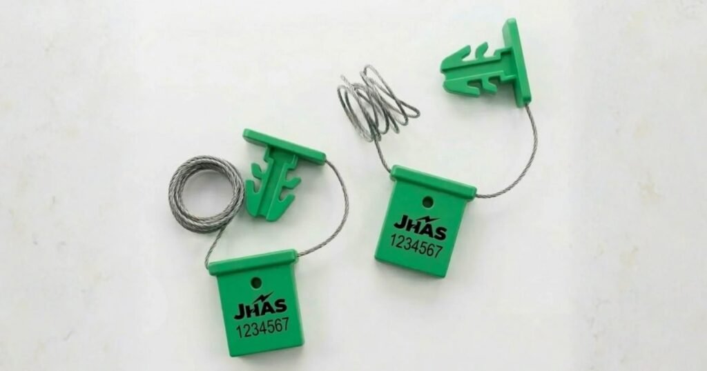 Two green safety tags with metal wire loops, labeled JHAS 1234567, on a light background.